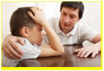 Image of a dad with his arm around a boy that has his head in his hands. 